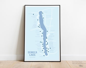 May include: A blue and white map of Seneca Lake in New York State, showing the location of wineries. The map is framed in a black frame and is hanging on a white wall.