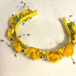May include: A yellow headband with yellow fabric flowers and gold beads.