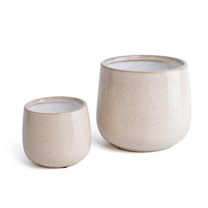 May include: Two speckled beige ceramic planters. The larger planter is slightly taller than the smaller one. Both have a rounded shape and a white interior. The planters are suitable for indoor or outdoor use.