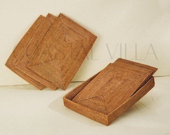 May include: Set of four woven wicker rectangular coasters. The coasters are stacked on top of each other, with the top coaster slightly offset from the others. The coasters are a light brown color and have a woven pattern.
