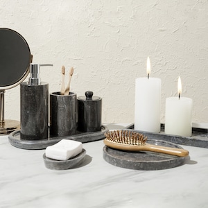 Peut inclure: Un ensemble d'accessoires de salle de bain en marbre gris et blanc. L'ensemble comprend un distributeur de savon, un porte-brosses à dents, un pot, un porte-savon, un plateau et une brosse à cheveux. Deux bougies blanches sont également incluses.