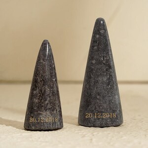 May include: Two gray marble cone-shaped objects with the date "20.12.2018" inscribed on the bottom.