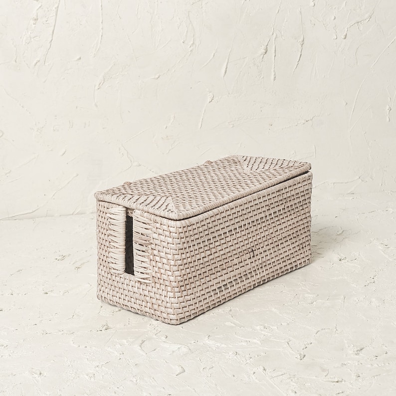 May include: White wicker storage box with a lid and a handle on the side. The box is woven with a fine, intricate pattern.