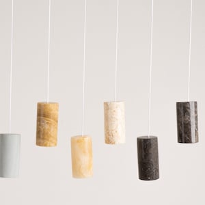 May include: Six different marble pull chains hanging from white cords. The pull chains are in various colors and patterns, including gray, beige, and brown.