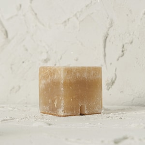 May include: A light brown, rectangular, natural stone planter with a rough, textured surface.