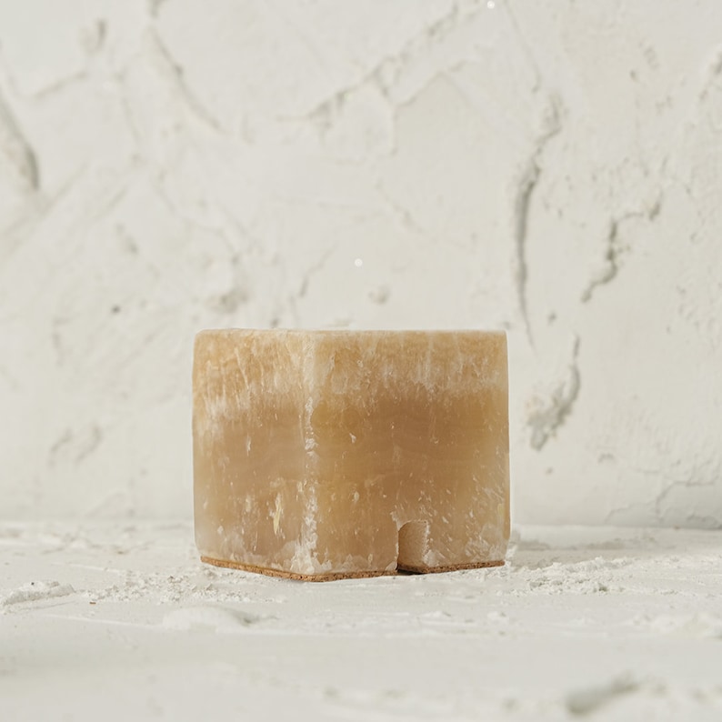 May include: A light brown, rectangular, natural stone planter with a rough, textured surface.