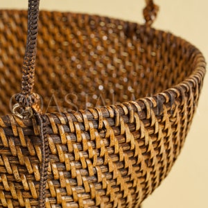 May include: A brown woven basket with a handle. The basket is made of natural materials and has a traditional design.