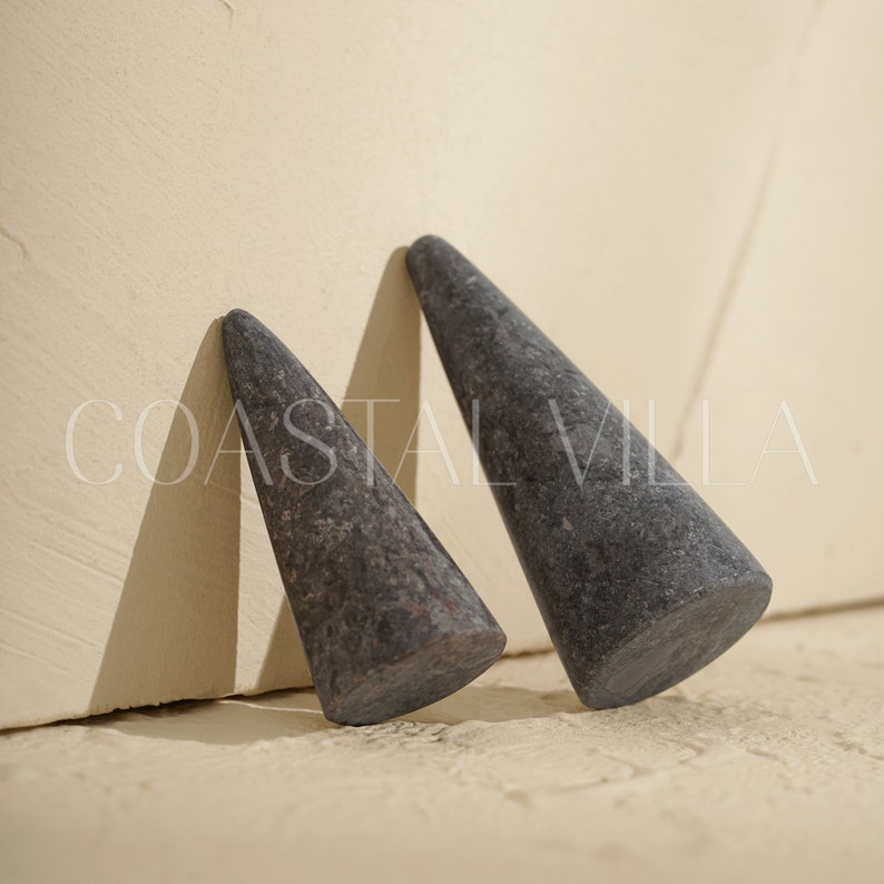 May include: Two gray stone cone-shaped objects. The cones are smooth and have a slightly textured surface.