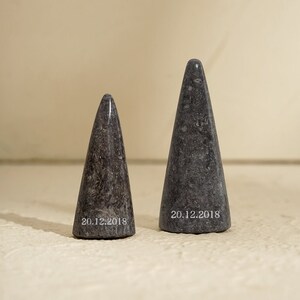 May include: Two gray marble cone-shaped objects with the date "20.12.2018" inscribed on the bottom.