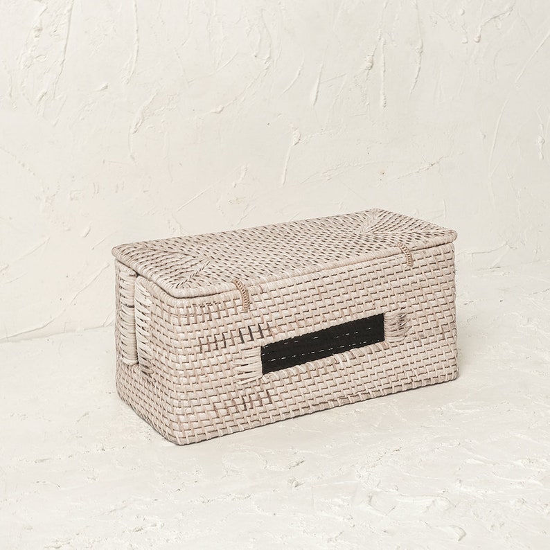 May include: White wicker storage box with a rectangular shape and a black opening on the front. The box is woven with a fine, intricate pattern.
