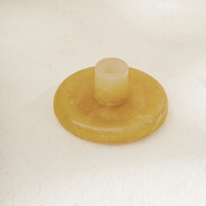 May include: A yellow, round, candle holder with a small, cylindrical, clear glass candle holder in the center.