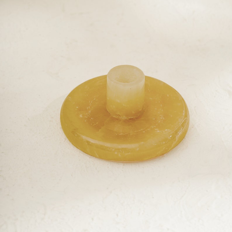May include: A yellow, round, candle holder with a small, cylindrical, clear glass candle holder in the center.