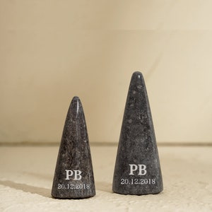 May include: Two gray marble cone-shaped objects with the initials "PB" and the date "20.12.2018" engraved on them.