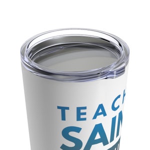 Puede incluir: Taza de acero inoxidable blanca con un dise&ntilde;o azul y blanco que dice "Teacher Saints".