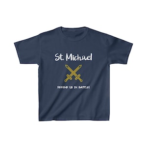 May include: Navy blue t-shirt with white text that reads "St. Michael" and a gold crossed swords graphic. The text below the graphic reads "Defend us in battle!"