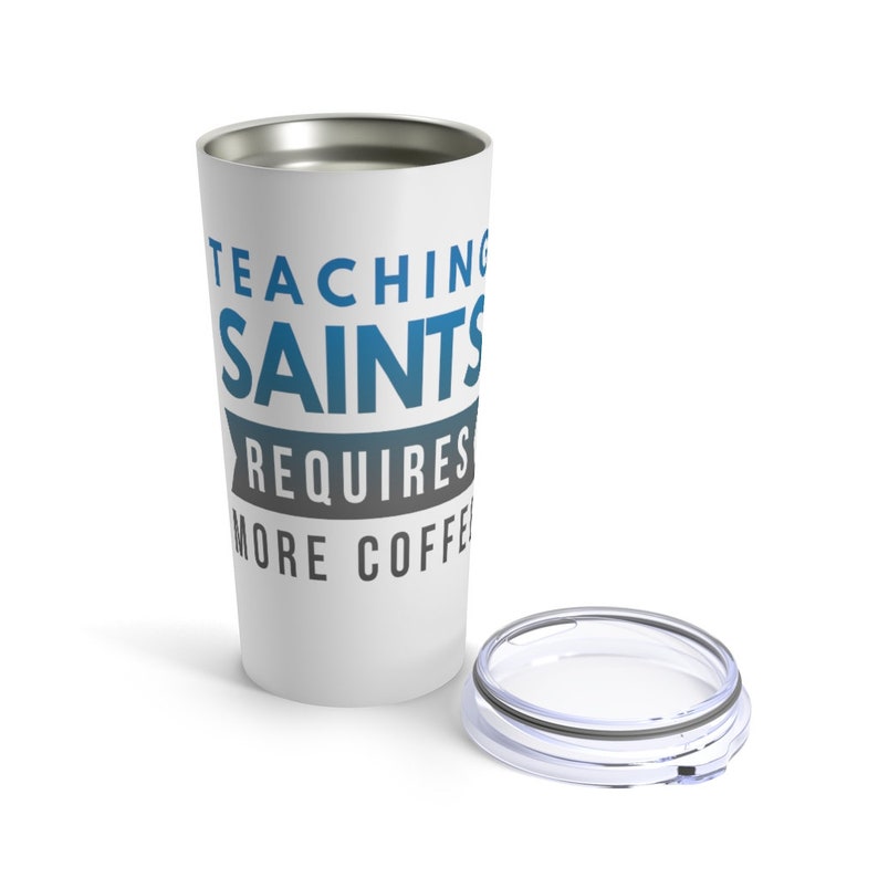Puede incluir: Taza de viaje de acero inoxidable blanca con un dise&ntilde;o azul y gris que dice "Ense&ntilde;ar a los santos requiere m&aacute;s caf&eacute;".