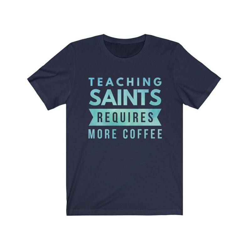 Peut inclure: T-shirt bleu marine avec un design d&eacute;grad&eacute; bleu clair et vert. Le texte "TEACHING SAINTS REQUIRES MORE COFFEE" est imprim&eacute; sur le t-shirt.