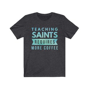 Peut inclure: T-shirt gris fonc&eacute; chin&eacute; avec un motif d&eacute;grad&eacute; bleu et vert. Le texte "Teaching Saints Requires More Coffee" est imprim&eacute; sur le t-shirt.