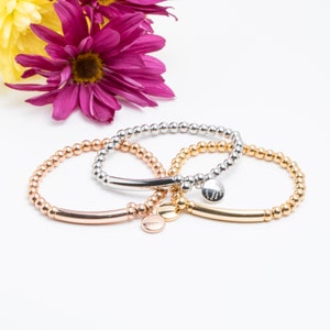 May include: Three beaded bracelets with a silver, gold, and rose gold finish. Each bracelet has a small charm with the word "Happiness" engraved on it.