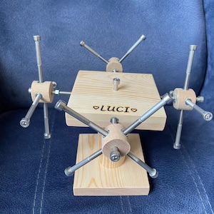 May include: A wooden stand with six metal arms extending out from the center. The stand is engraved with the word "LUCI" and a heart symbol.