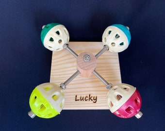 May include: A wooden toy with four colorful balls attached to a central rotating axis. The balls are half white and half a different color: green, blue, yellow, and red. The base of the toy is engraved with the word "Lucky".