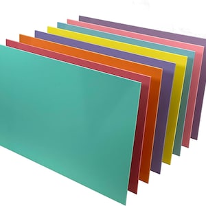 May include: A stack of ten colorful sheets of paper in various shades of pink, orange, yellow, green, purple, and blue. The sheets are arranged in a fan shape, with the top sheet being a light turquoise color.