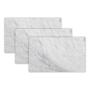 May include: Three white marble cutting boards of different sizes, stacked on top of each other.
