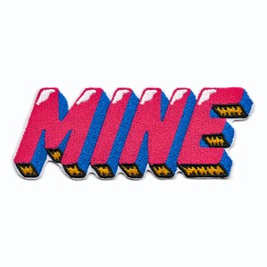 Puede incluir: Un parche bordado con la palabra "MINE" en letras en negrita 3D, de color rosa y azul.