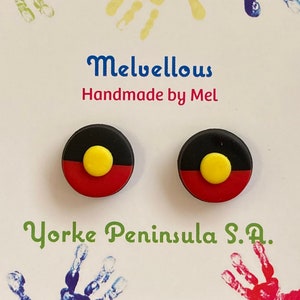 May include: A pair of small, round earrings featuring the Aboriginal flag. The earrings are made of polymer clay and are black, yellow, and red. The earrings are handmade by Mel and are available for purchase on Etsy.