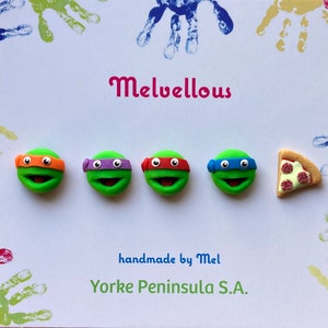 May include: Four green turtle-shaped clay figures with orange, purple, red, and blue eye masks, alongside a slice of pepperoni pizza. The white background features colourful handprints and the text Melvellous, handmade by Mel, Yorke Peninsula S.A.