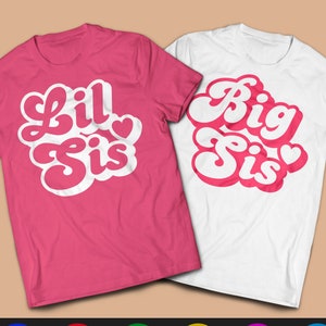 Könnte beinhalten: Zwei T-Shirts mit einem Retro-Schriftart-Design. Ein Shirt ist pink mit dem Text "Lil Sis" und das andere ist weiß mit dem Text "Big Sis".