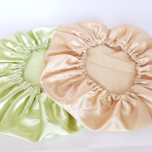 Puede incluir: Dos gorros de sat&eacute;n. Uno es de color verde claro y el otro de color beige claro. Ambos gorros tienen una banda el&aacute;stica alrededor del borde para mantenerlos en su lugar. Los gorros est&aacute;n hechos de una tela brillante y suave.