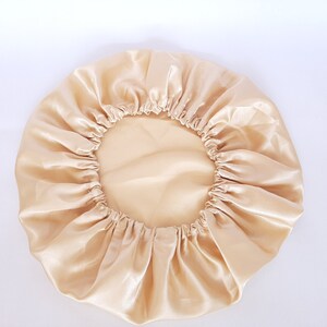 Puede incluir: Un gorro de sat&eacute;n de color beige claro. El gorro es redondo con una banda el&aacute;stica en el borde. La tela tiene una textura brillante y suave. El gorro est&aacute; dise&ntilde;ado para proteger el cabello mientras se duerme.