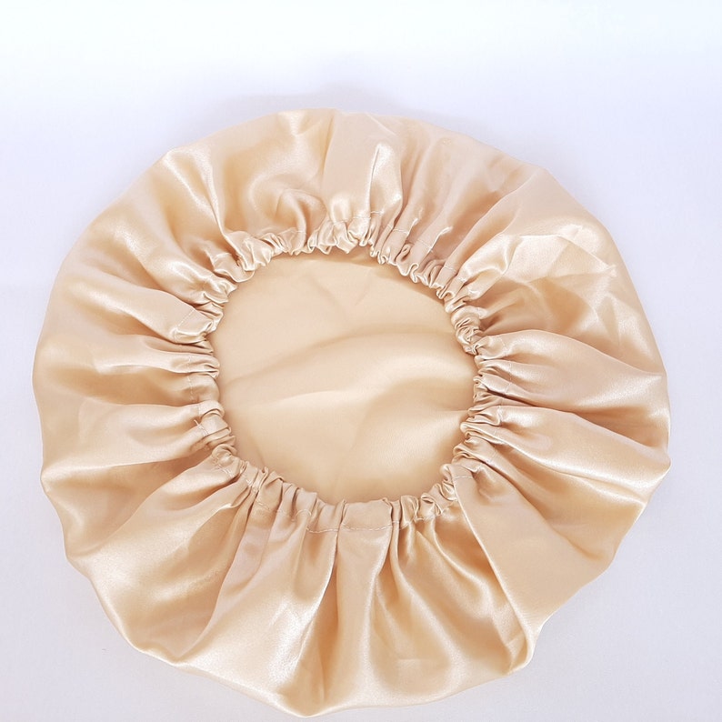 Puede incluir: Un gorro de sat&eacute;n de color beige claro. El gorro es redondo con una banda el&aacute;stica en el borde. La tela tiene una textura brillante y suave. El gorro est&aacute; dise&ntilde;ado para proteger el cabello mientras se duerme.
