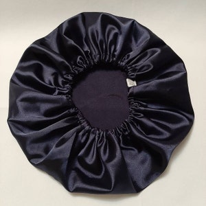 Puede incluir: Un gorro de sat&eacute;n azul marino oscuro con una banda el&aacute;stica. El gorro es redondo con un dise&ntilde;o fruncido y una textura suave y brillante. El interior es un tono m&aacute;s oscuro de azul marino.