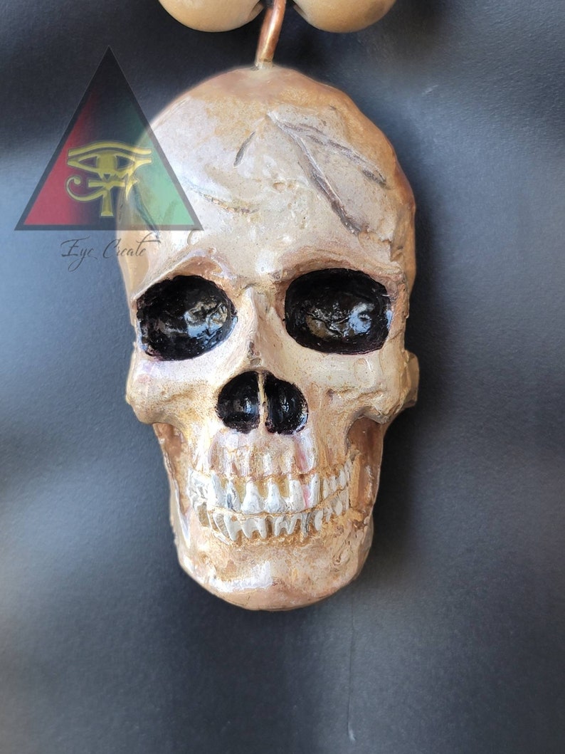 May include: A gold-painted human skull with black eye sockets and a painted smile. The skull is a decorative object.