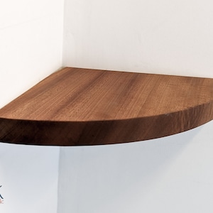 A mahogany shelf is installed on the corner of a wall.