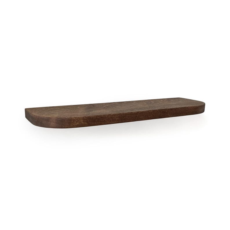 A single floating wall shelf made of walnut, dark brown stained wood. The shelf features a rectangular shape with rounded edges on the front corners, showcasing a visible wood grain texture throughout the surface of the horizontal board.