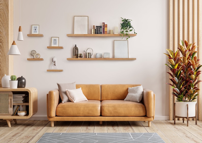 Two hands grip the top and bottom of the front piece of a long wooden oak shelf and easily install it onto the wall by sliding the shelf onto black brackets.