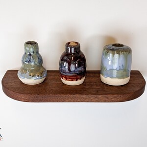 Top view of a mahogany floating shelf with three vases as decor