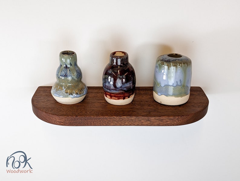 Top view of a mahogany floating shelf with three vases as decor