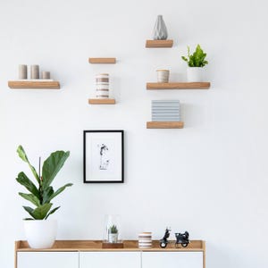 Thin oak shelves displayed on wall with decor items.