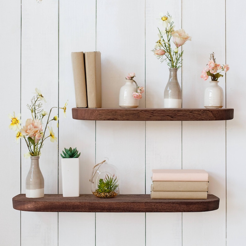 Mahogany shelves with rounded corners on a wooden wall with decor.