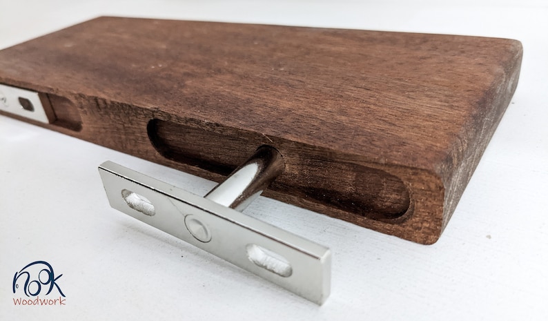 Pu&ograve; includere: Un supporto per mensola in legno con un supporto a T in metallo argentato. Il supporto &egrave; in legno marrone scuro e ha una finitura liscia. Il supporto metallico &egrave; fissato al supporto con viti.
