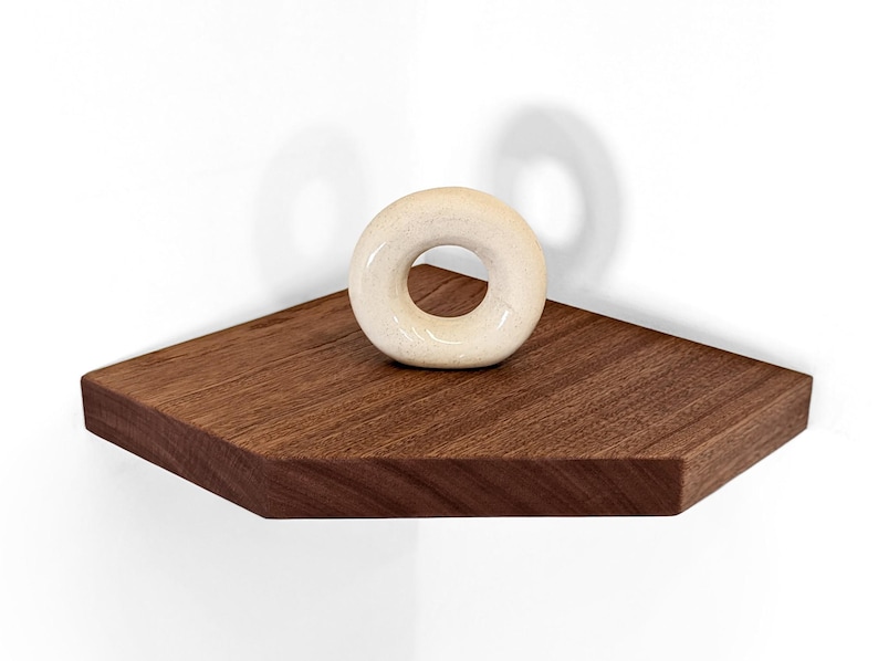 Front view of a mahogany floating shelf displaying a donut sculpture.