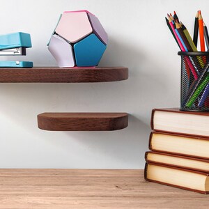Two thin mahogany shelves with rounded corners are displayed on a wall over a desk.