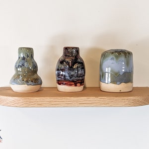 Front view of three vases sitting atop an oak shelf with soft beveled and rounded corners
