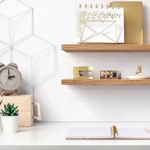 Two thin oak shelves are displayed on a wall above a desk.