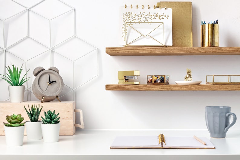 Two thin oak shelves are displayed on a wall above a desk.