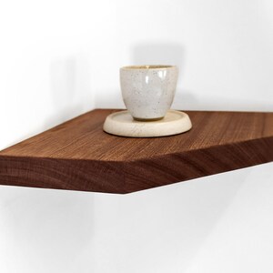 Side view of a mahogany corner floating shelf displaying a candle.